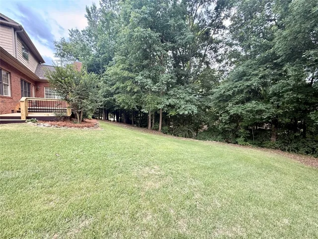 A verdant backyard with mature trees and a spacious deck awaits outdoor gatherings.