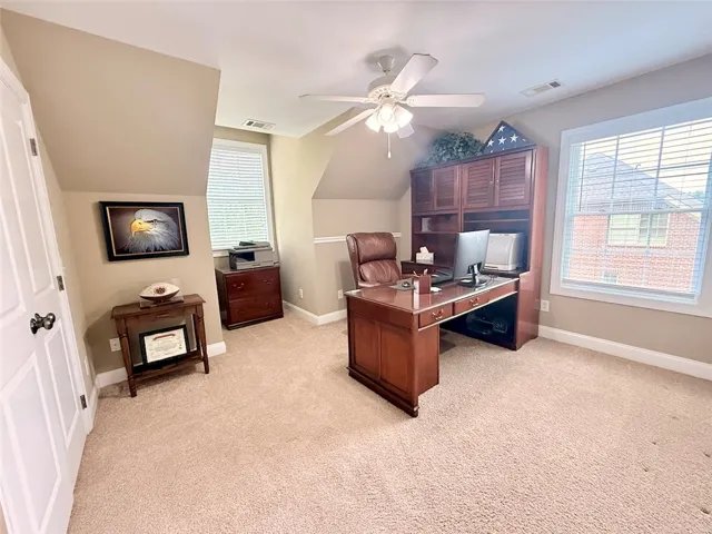 A well-appointed home office offers comfort and productivity with soft carpeting and ample natural light.  Spacious walk-in closet