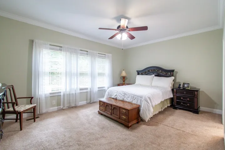 Well-lit sleeping quarters with elegant crown molding and a practical ceiling fan for comfort.