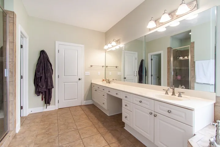 A generously sized bathroom features dual vanities and an adjoining glass-enclosed shower.