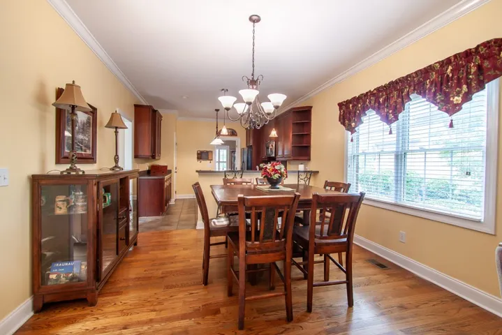 Natural light illuminates this inviting dining space, featuring rich hardwood floors and crown molding.