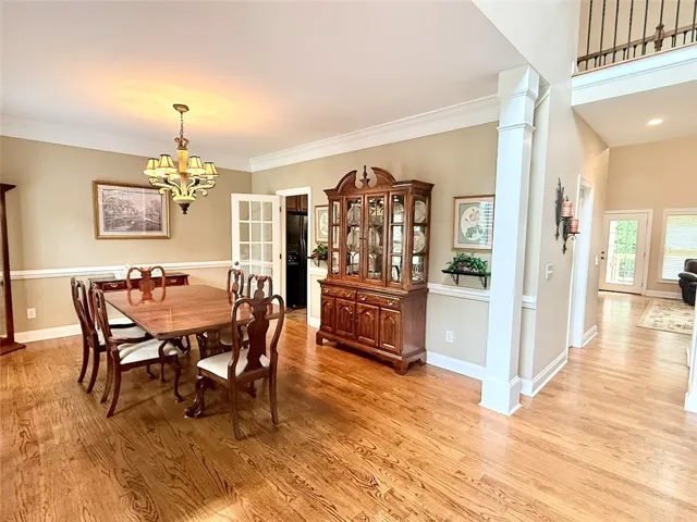 Hardwood floors stretch across this elegant dining room, illuminated by a classic chandelier.