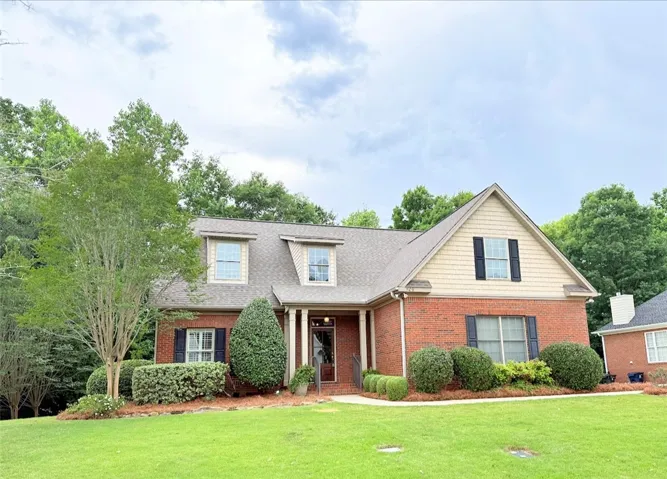 A classic brick exterior with dormer windows and mature landscaping creates appealing curb appeal.