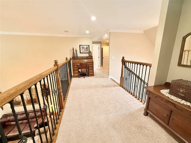 Second-story landing features plush carpeting and wrought iron balusters overlooking the living space below.