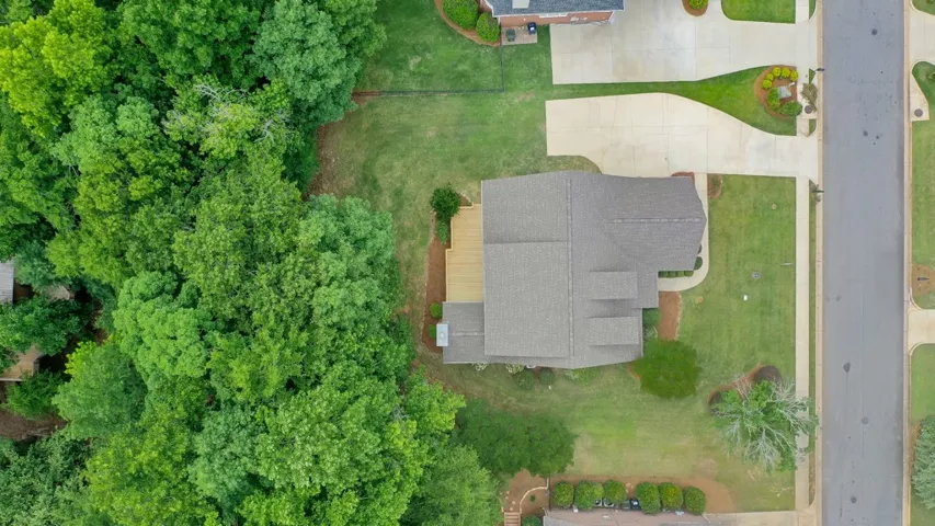 An aerial perspective showcases a well-maintained home with ample outdoor space and mature trees.