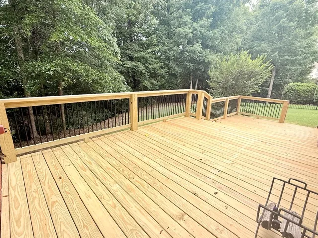 An inviting new deck extends into a lush, private yard surrounded by mature trees.