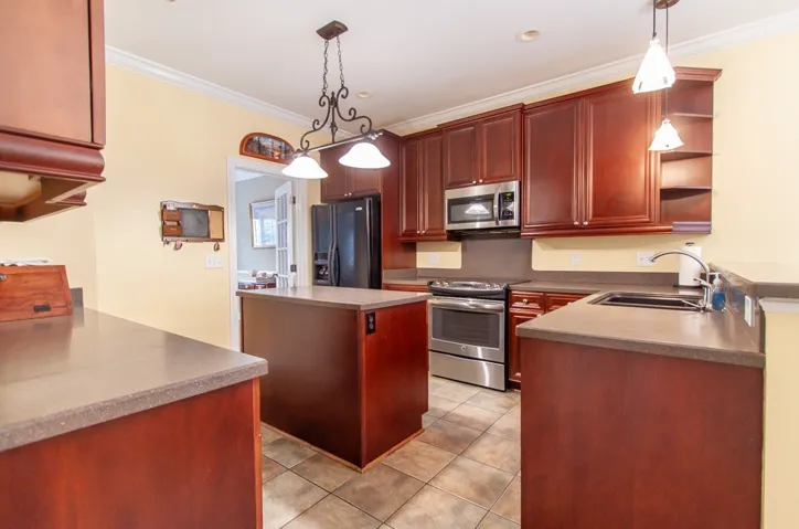 A well-appointed kitchen features rich cabinetry, practical island, and modern stainless steel appliances.