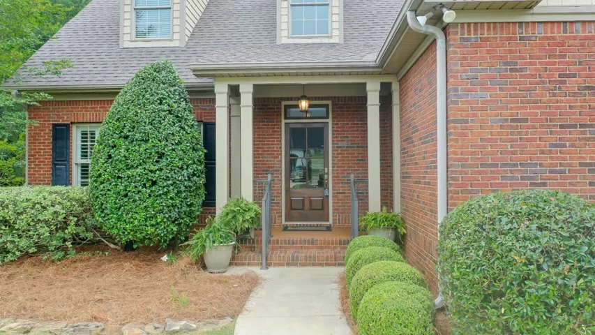A classic brick exterior welcomes guests with a covered entry and manicured shrubs.
