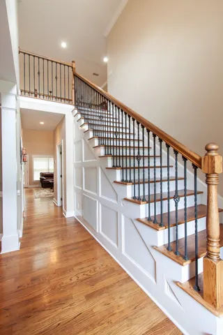 A grand staircase with rich wooden treads and wrought iron balusters anchors the airy entry, complemented by lustrous hardwood floors.