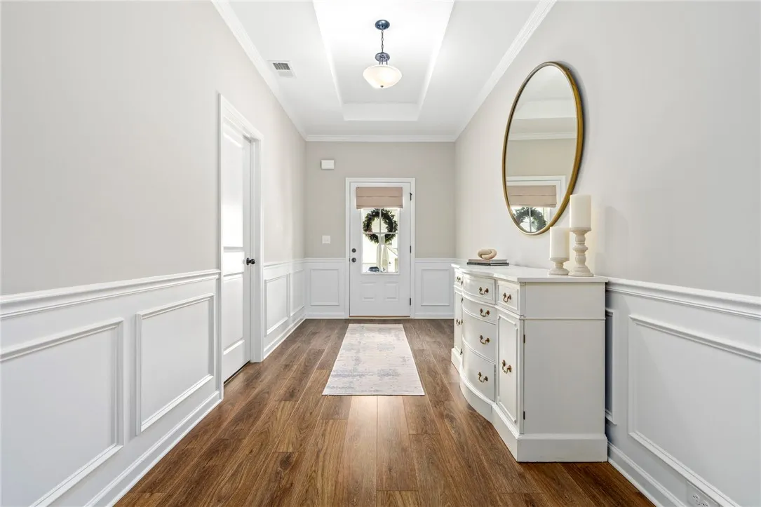 A graceful entry with warm wood flooring and classic wainscoting welcomes all who enter.