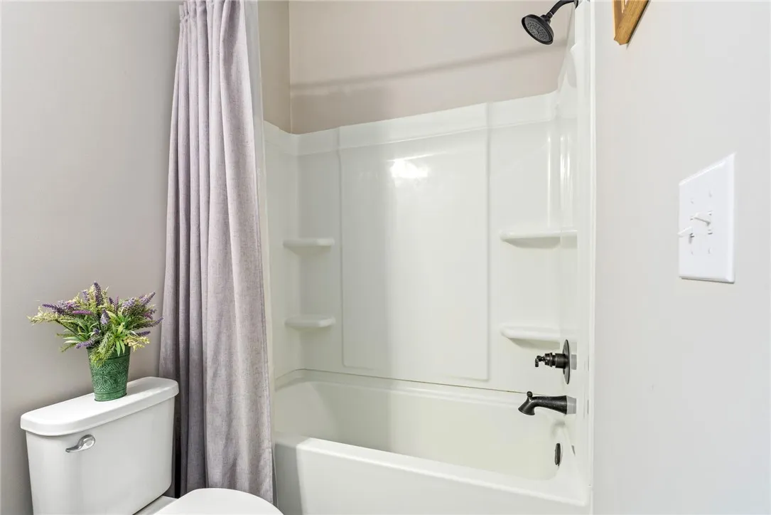 Functional bath features a white tub and shower combination with dark bronze fixtures.