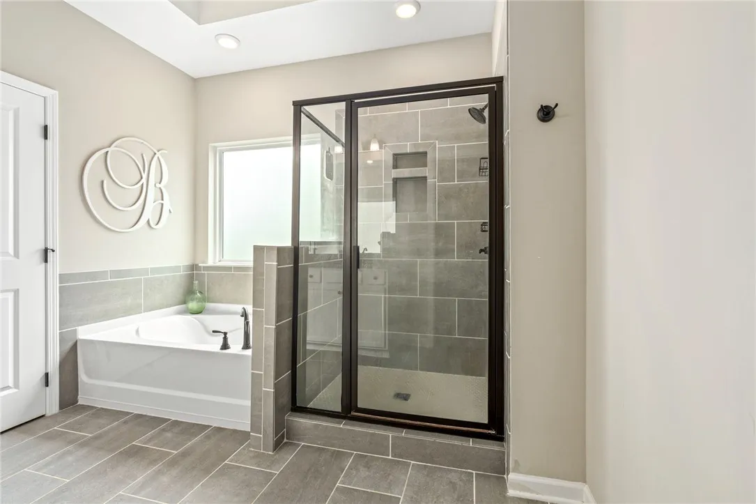 A well-lit bathroom features a deep soaking tub and a spacious glass-enclosed shower.