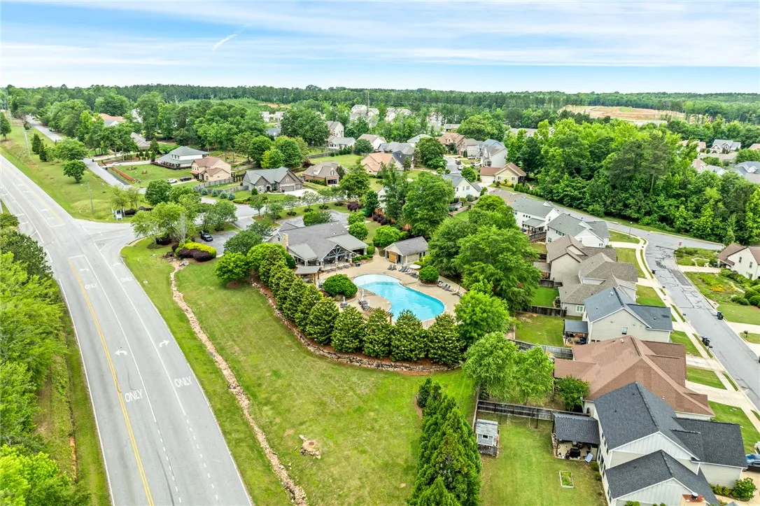 An aerial panorama showcases a vibrant community with an inviting pool area, surrounded by verdant trees and well-maintained streets.