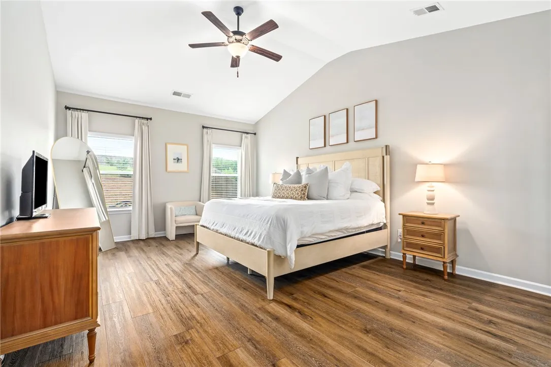 Hardwood floors and vaulted ceilings elevate this well-lit primary bedroom.
