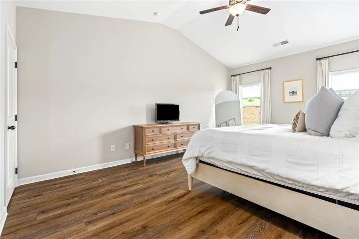 Hardwood floors and a vaulted ceiling elevate this primary bedroom.