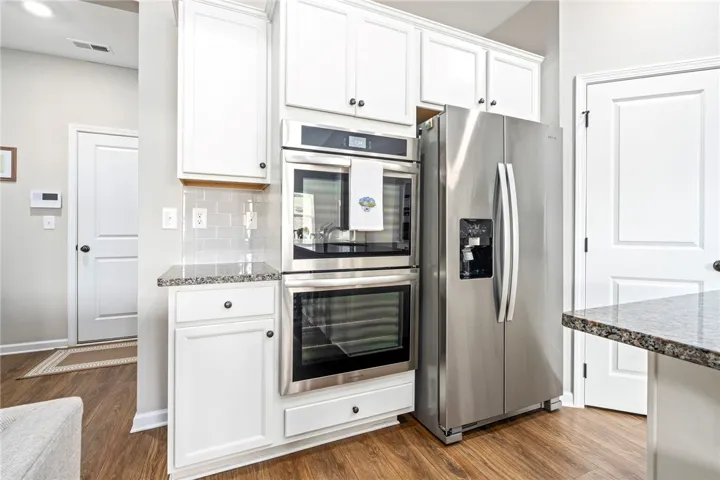 A contemporary kitchen showcasing integrated double ovens and a stainless steel refrigerator.