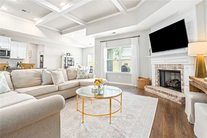A welcoming living area showcases a cozy fireplace and attractive coffered ceilings.