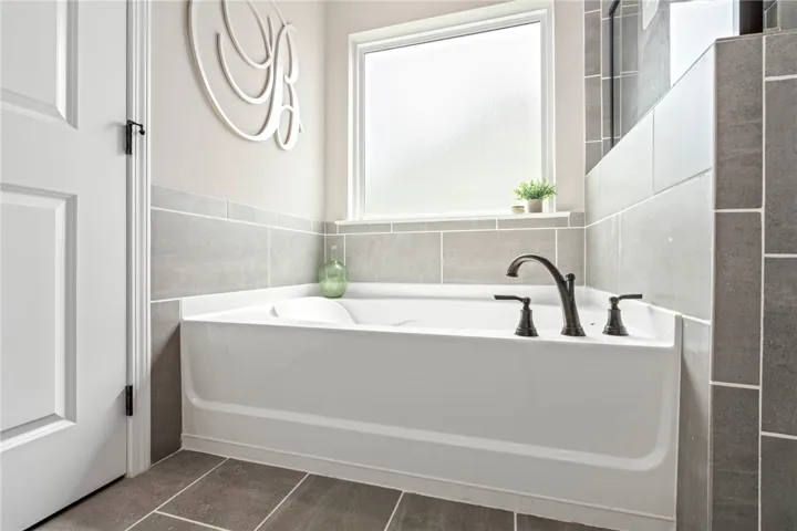 Indulge in a tranquil soak within this well-appointed bathroom featuring a deep tub and elegant fixtures.