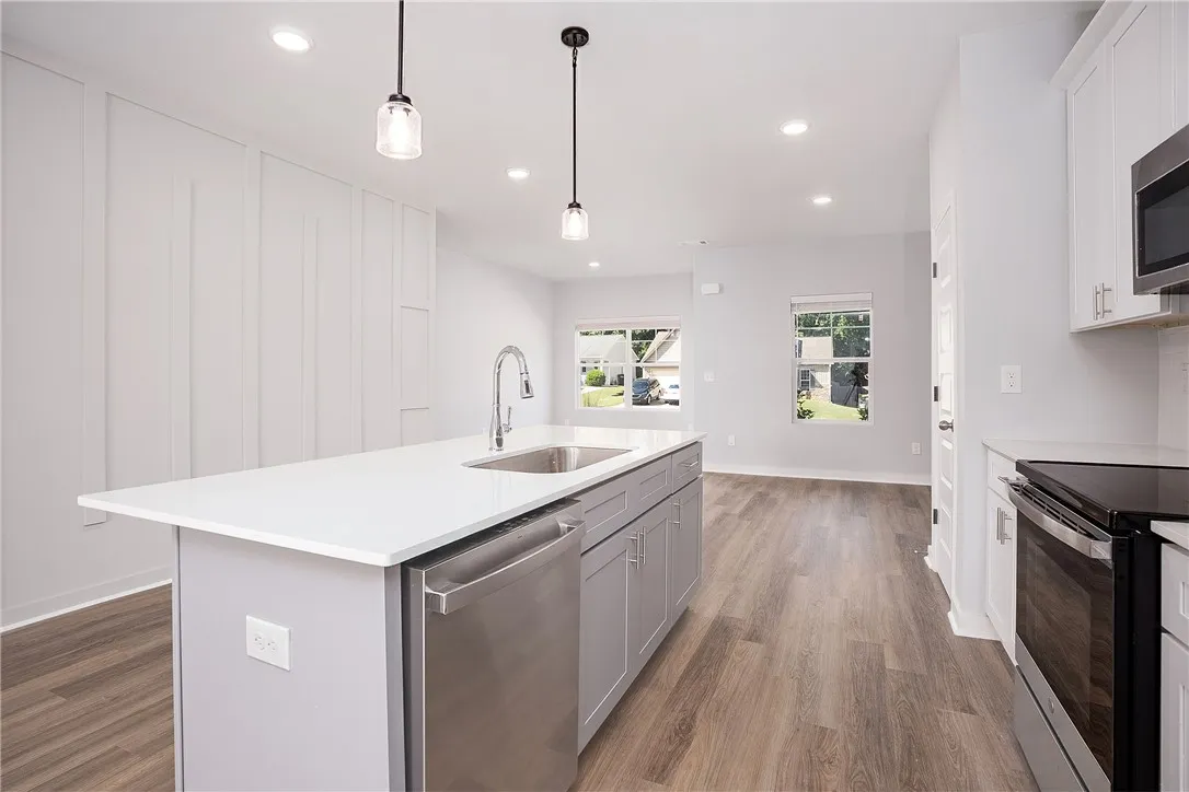 A contemporary kitchen boasts a spacious island and seamlessly connects to a sun-filled living area.