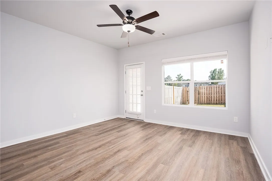 A well-lit room showcasing rich hardwood flooring and a functional ceiling fan.