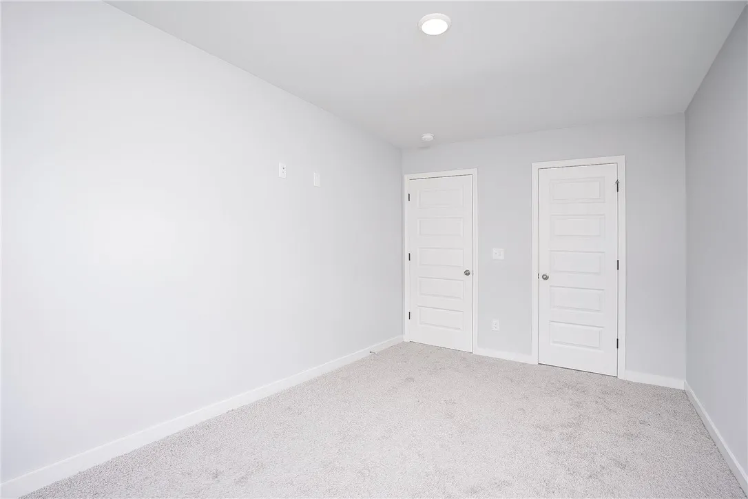 Two paneled doors provide access in this neutrally carpeted bedroom.