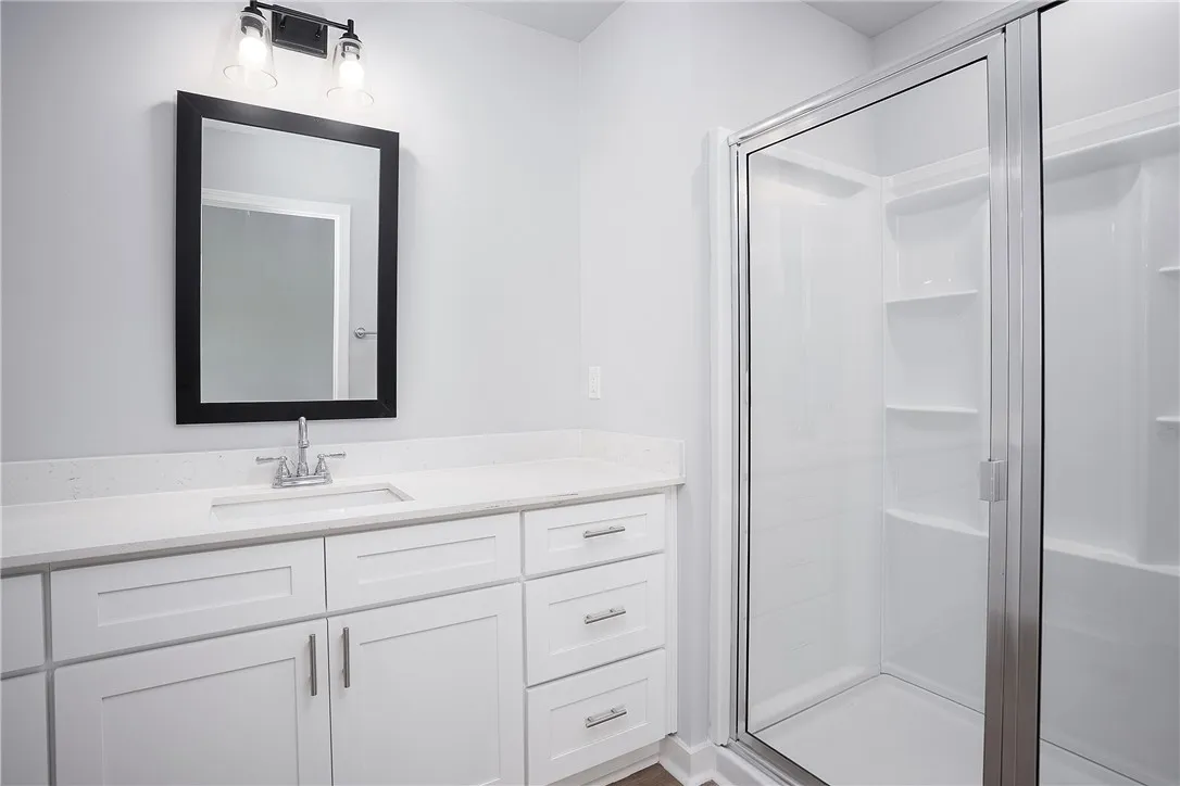 A well-lit bathroom features a spacious vanity with clean lines and a convenient stand-up shower.