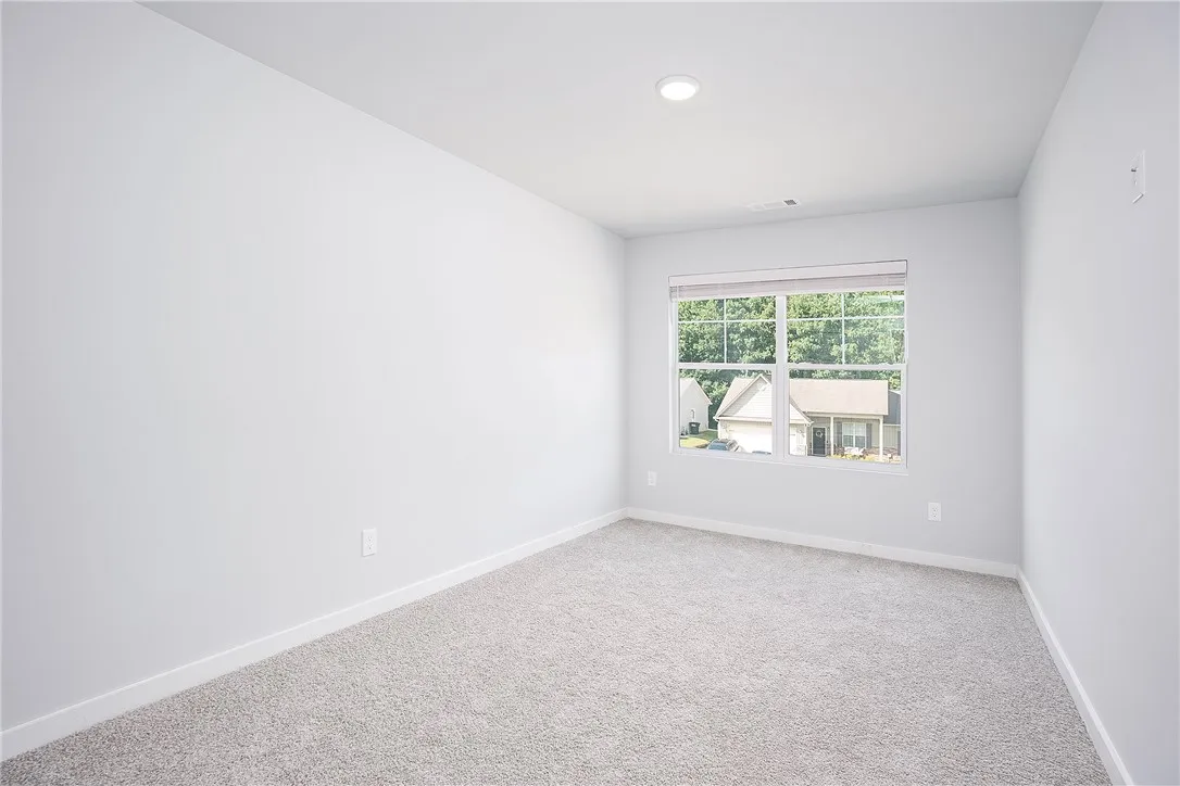 A spacious room offers ample natural light and plush carpeting, ready for personalization.