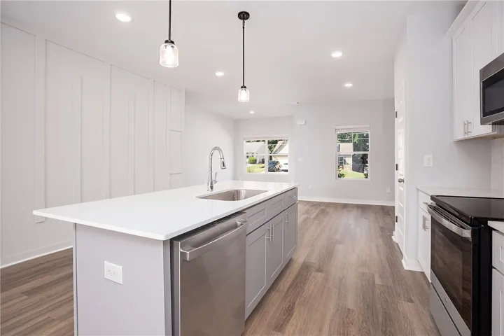 A contemporary kitchen boasts a spacious island and seamlessly connects to a sun-filled living area.