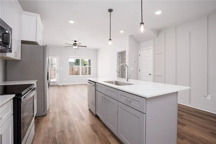 Modern kitchen features a spacious island with a sink, sleek cabinetry, and stainless steel appliances.