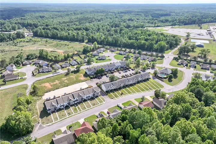 An aerial perspective reveals a charming residential community nestled amongst lush green woodlands.