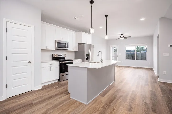 Modern kitchen with an inviting island and stainless steel appliances, seamlessly flowing into a spacious living area.