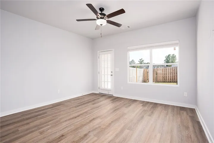 A well-lit room showcasing rich hardwood flooring and a functional ceiling fan.