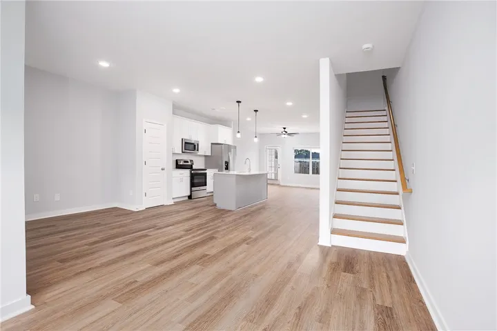 An open-concept living space with a contemporary kitchen flows seamlessly into a bright dining area, featuring sleek wood flooring and recessed lighting.