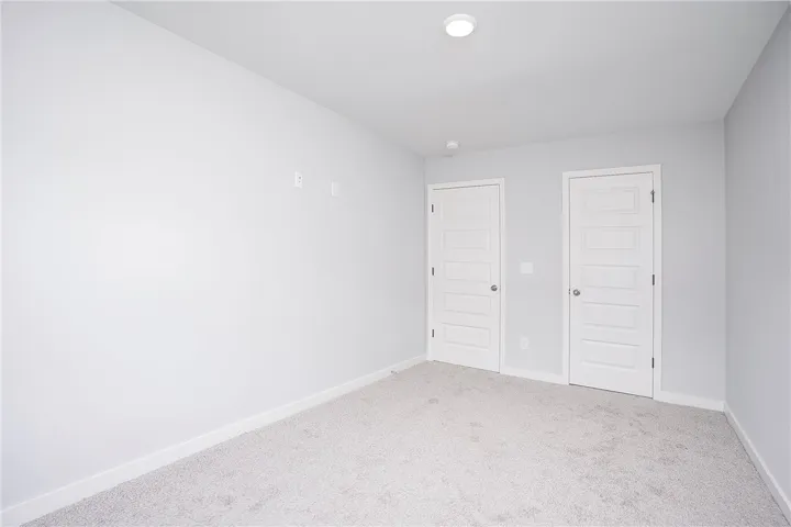 Two paneled doors provide access in this neutrally carpeted bedroom.