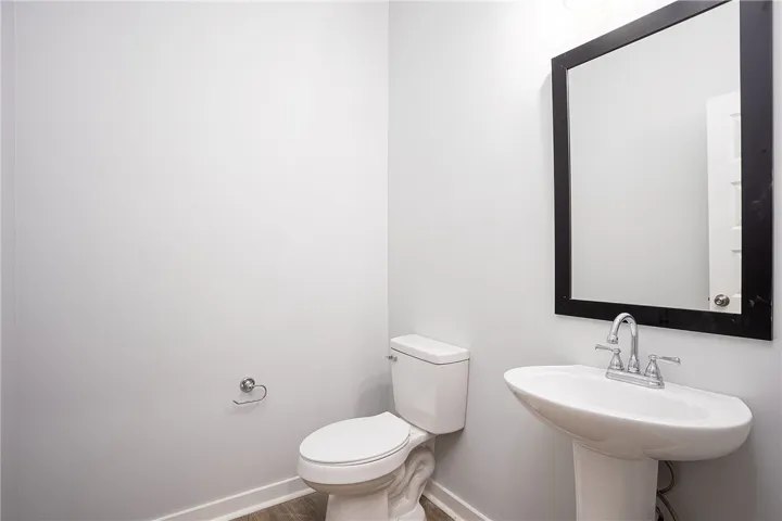 A well-appointed lavatory, featuring a pedestal sink and contemporary mirror.