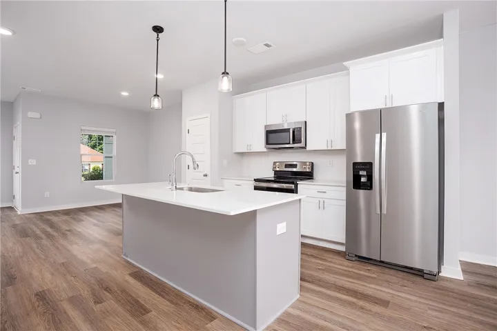 A well-appointed kitchen showcasing an island with a sink, white cabinetry, and stainless steel appliances.