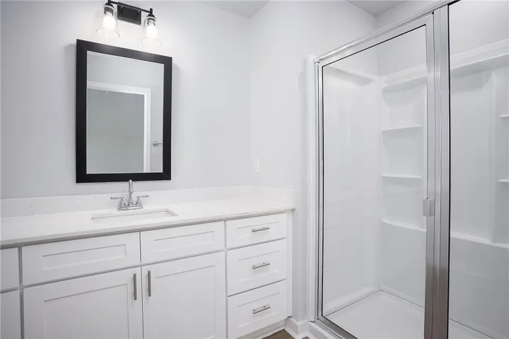 A well-lit bathroom features a spacious vanity with clean lines and a convenient stand-up shower.