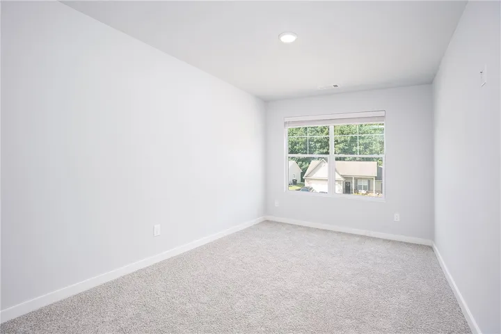A spacious room offers ample natural light and plush carpeting, ready for personalization.