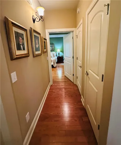 A well-lit hallway with gleaming wood floors invites movement through this elegant dwelling.