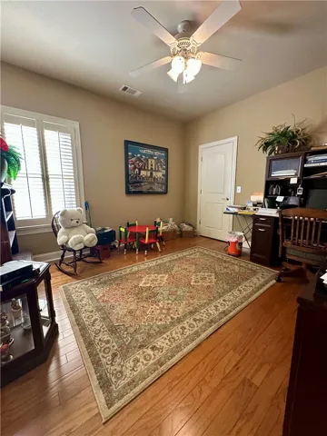 Hardwood floors and a ceiling fan create a comfortable atmosphere in this versatile room.