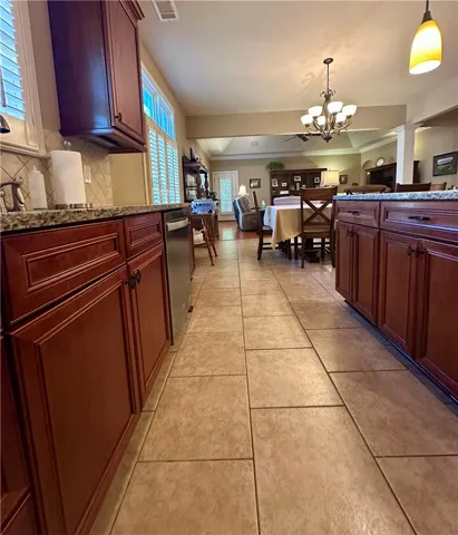 A well-lit kitchen with granite counters and rich wood cabinetry, offering an open flow into the dining and living spaces.