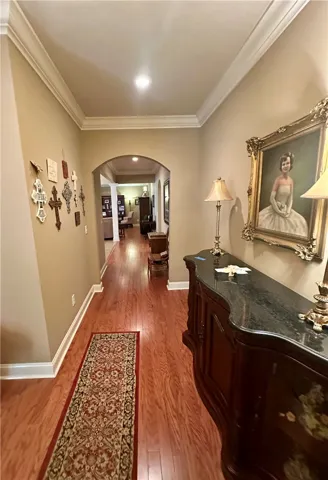 Rich hardwood floors guide the eye through an arched entryway into the home's inviting interior.
