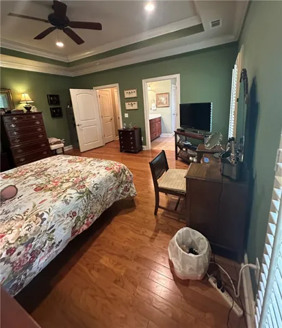 Rich hardwood flooring and tray ceilings enhance this spacious bedroom, offering an adjoining bathroom for ultimate comfort.