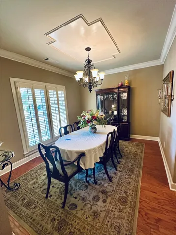 Elegant dining space featuring a striking tray ceiling and rich hardwood floors.