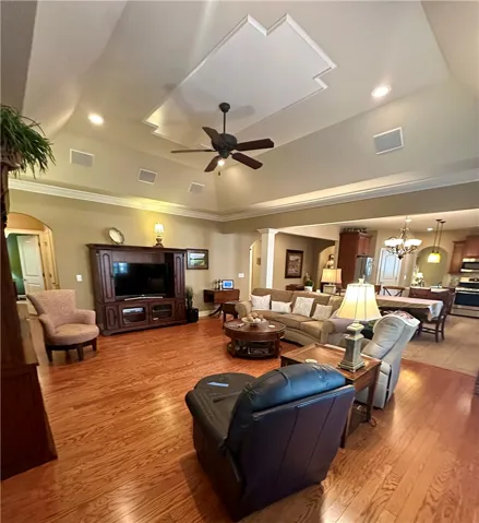 A spacious living room featuring warm hardwood flooring and a recessed ceiling design.