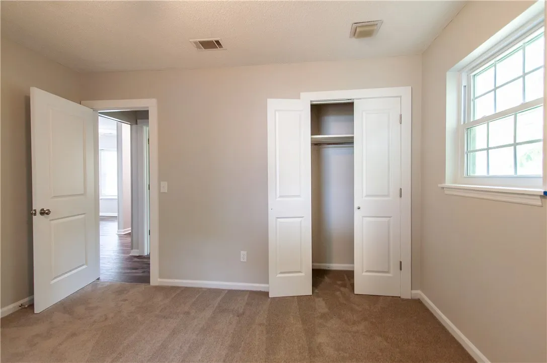 Well-lit sleeping quarters with a built-in closet and an adjacent doorway offering connectivity.