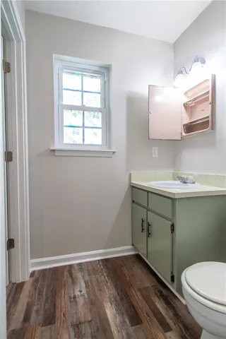 Bright, naturally illuminated bathroom with wood-style flooring and a window providing refreshing ventilation.