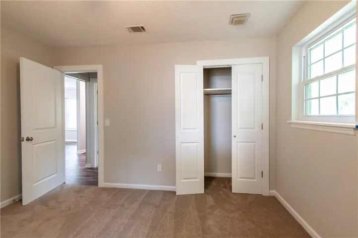 Well-lit sleeping quarters with a built-in closet and an adjacent doorway offering connectivity.