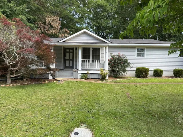 A welcoming front porch and mature trees adorn this classic suburban home.