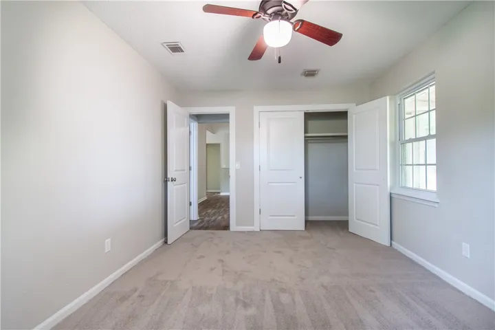 A well-lit bedroom featuring a ceiling fan and a window, offering a pleasant living space.